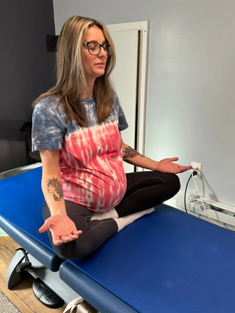 An expecting mom sitting comfortably cross-legged during an energy work session at Better Life Chiropractic in Groton, CT