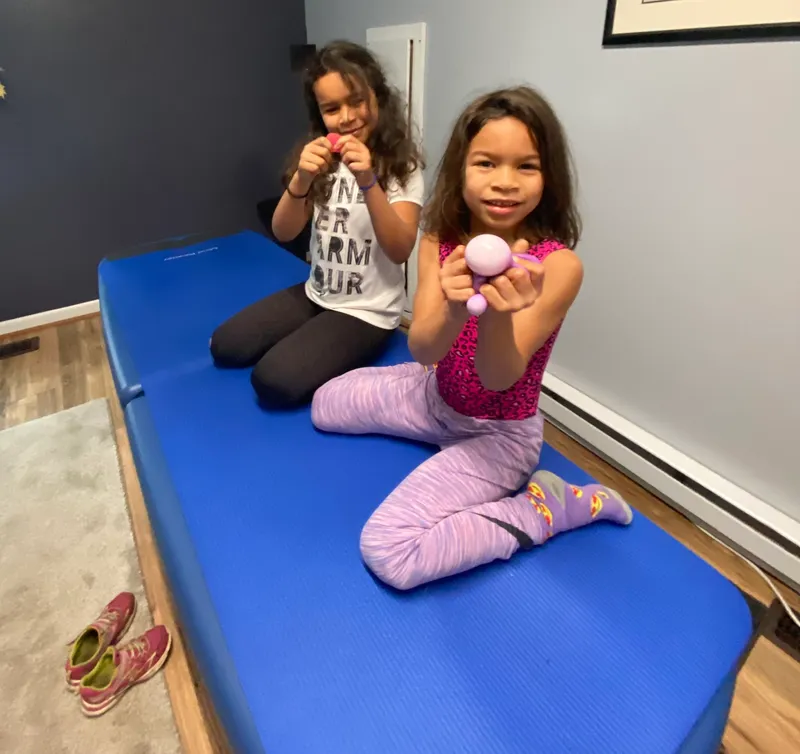 Two smiling kids playing on the adjustment table at Better Life Chiropractic in Groton, CT